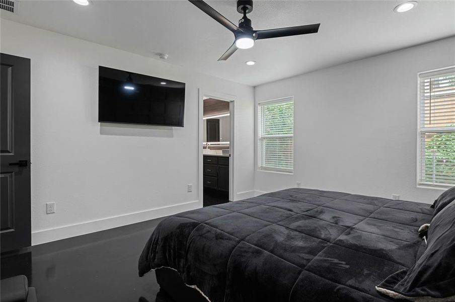 Bedroom featuring ceiling fan, multiple windows, and ensuite bath