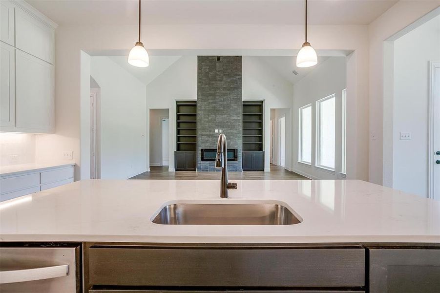 Kitchen with sink, light stone counters, vaulted ceiling, and white cabinetry