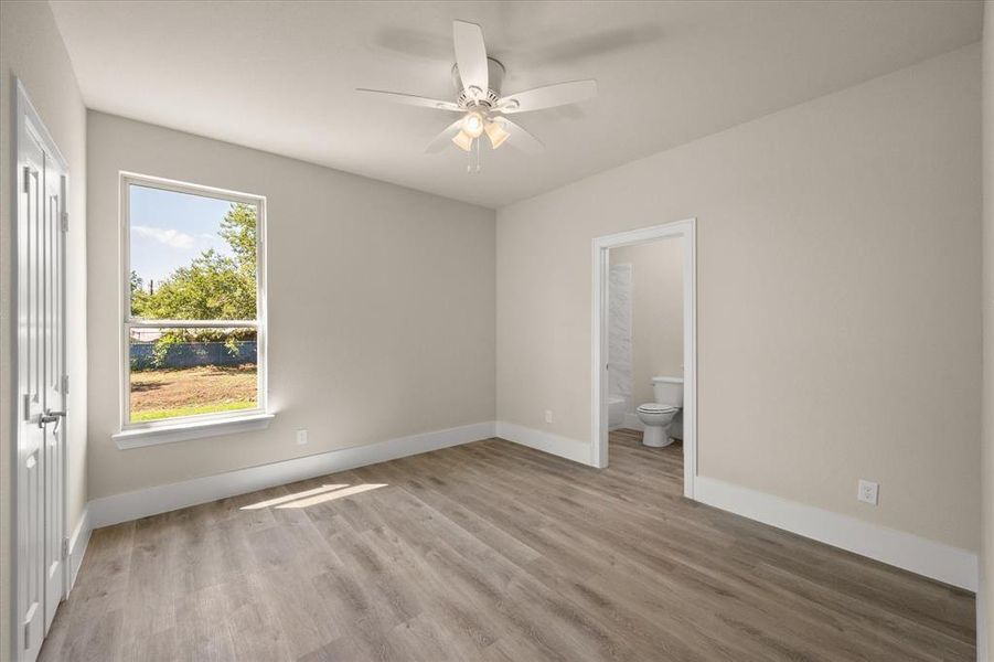 Unfurnished bedroom with ensuite bath, ceiling fan, and wood-type flooring