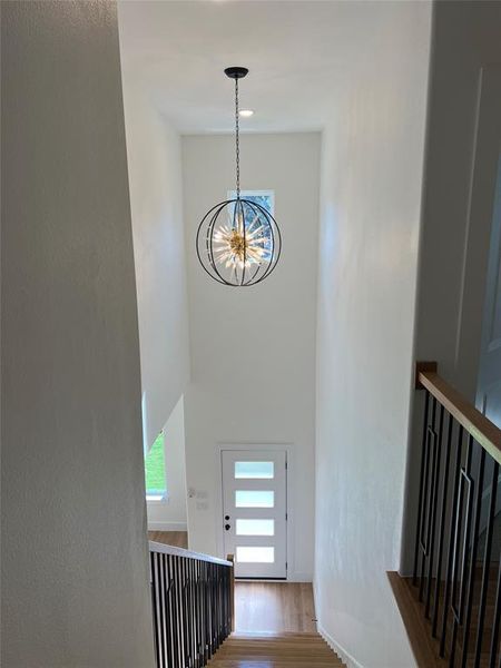 Stairs featuring an inviting chandelier and hardwood / wood-style flooring