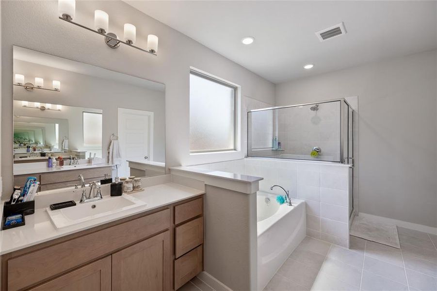 Bathroom with separate shower and tub, tile patterned floors, and vanity