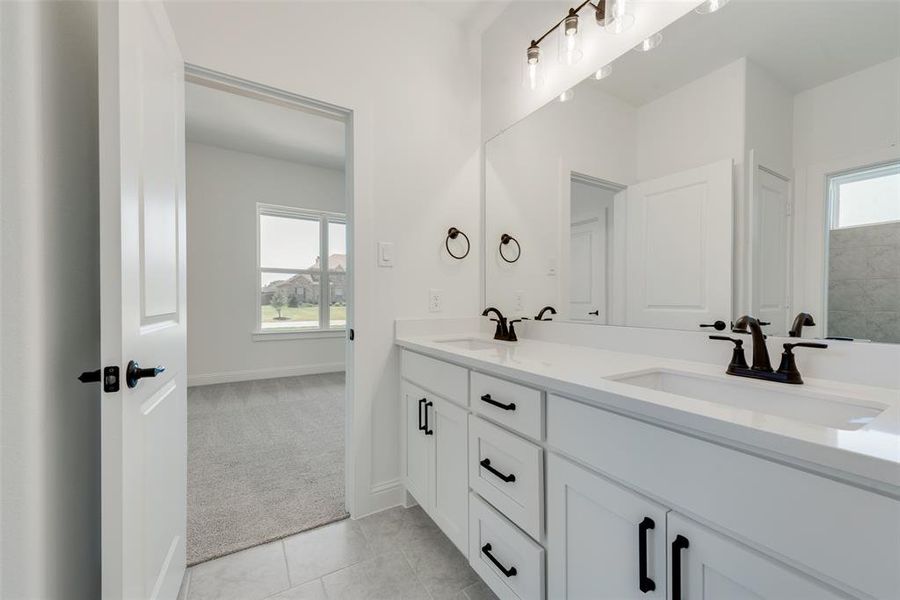Bathroom featuring dual vanity, tile patterned flooring, and a wealth of natural light