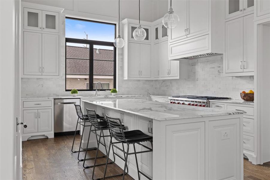 The gorgeous kitchen area features custom cabinetry custom built cabinets with inset soft close doors and drawers, designer lighting, and a marble island with seating and storage. A huge pantry offers additional convenient storage. Image from previously completed home in the community.