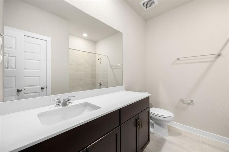 Secondary bathroom features Quartz countertops and bright cabinets, neutral paint, shower/tub combo with tile surround, large mirror, tile floors, sleek fixtures and modern finishes, plenty of space to accommodate any visiting family or guests.