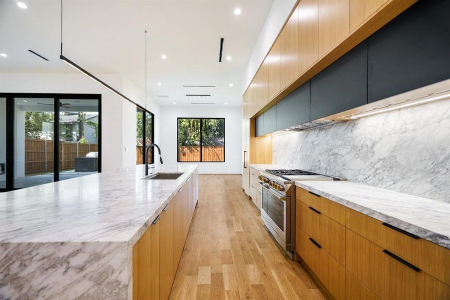 Kitchen featuring sink, a large island, light hardwood / wood-style flooring, backsplash, and stainless steel stove