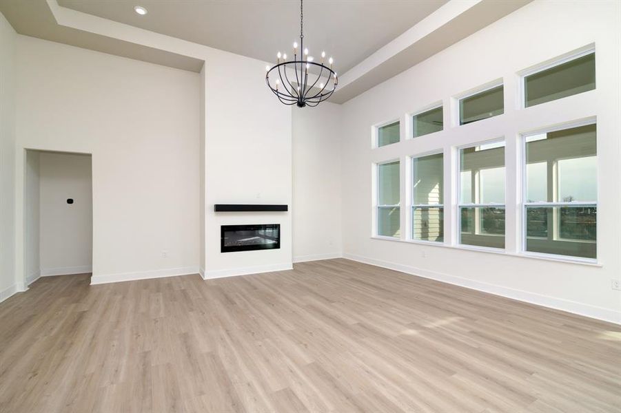 Unfurnished living room with a tray ceiling, light hardwood / wood-style floors, and an inviting chandelier