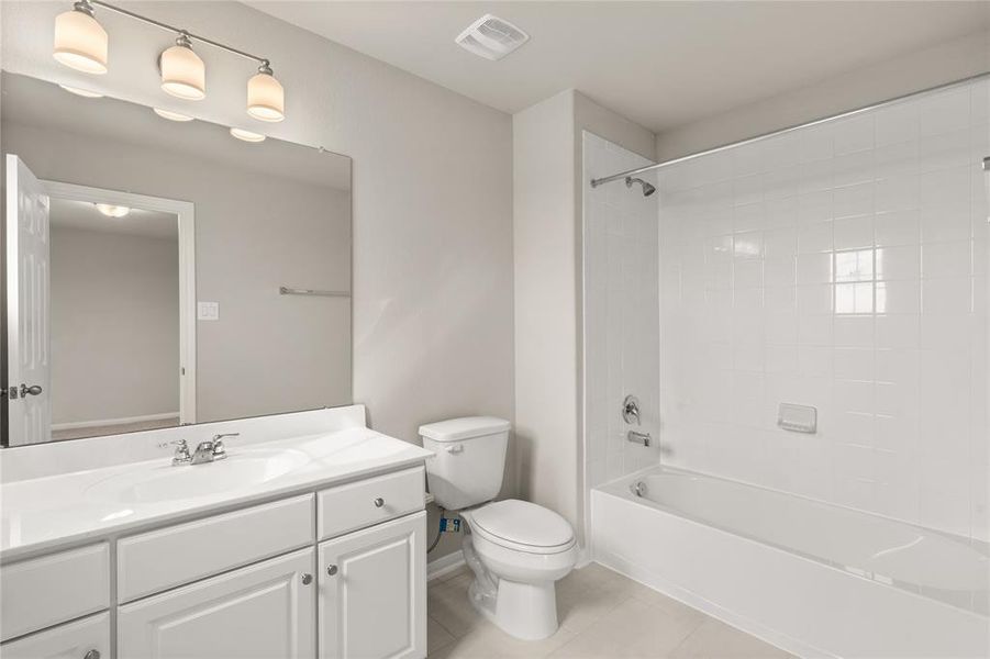 The secondary bath features tile flooring, white cabinetry and light countertops and a shower/tub combo.