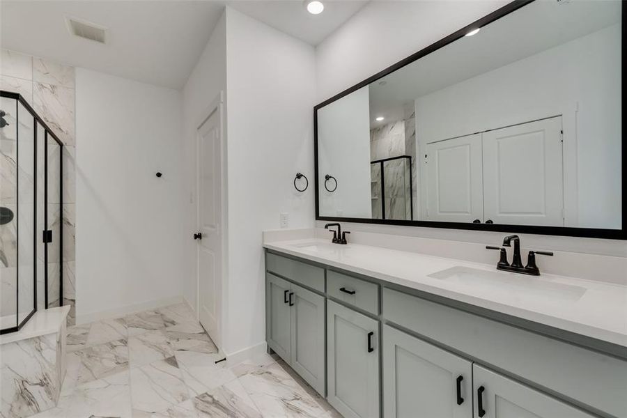 Bathroom featuring tile patterned floors, dual vanity, and a shower with shower door