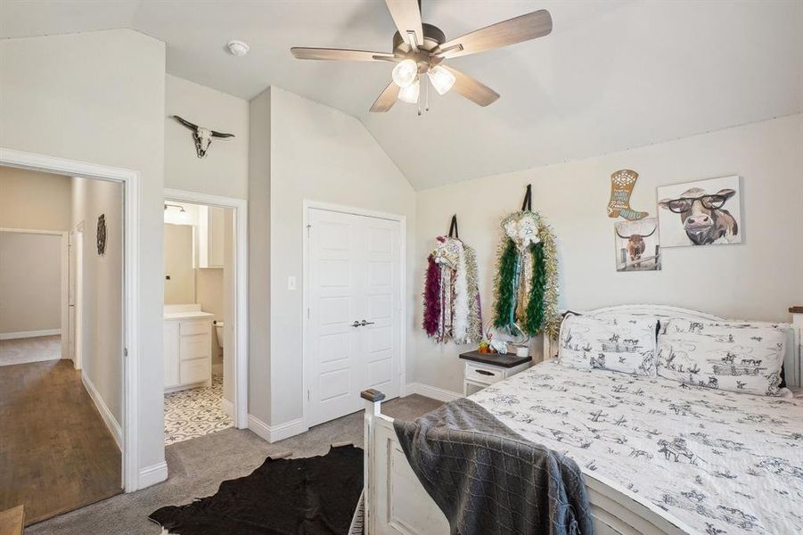 Carpeted bedroom with vaulted ceiling, ceiling fan, and a closet