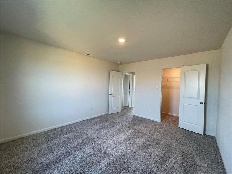 Unfurnished bedroom with dark colored carpet, a closet, and a walk in closet