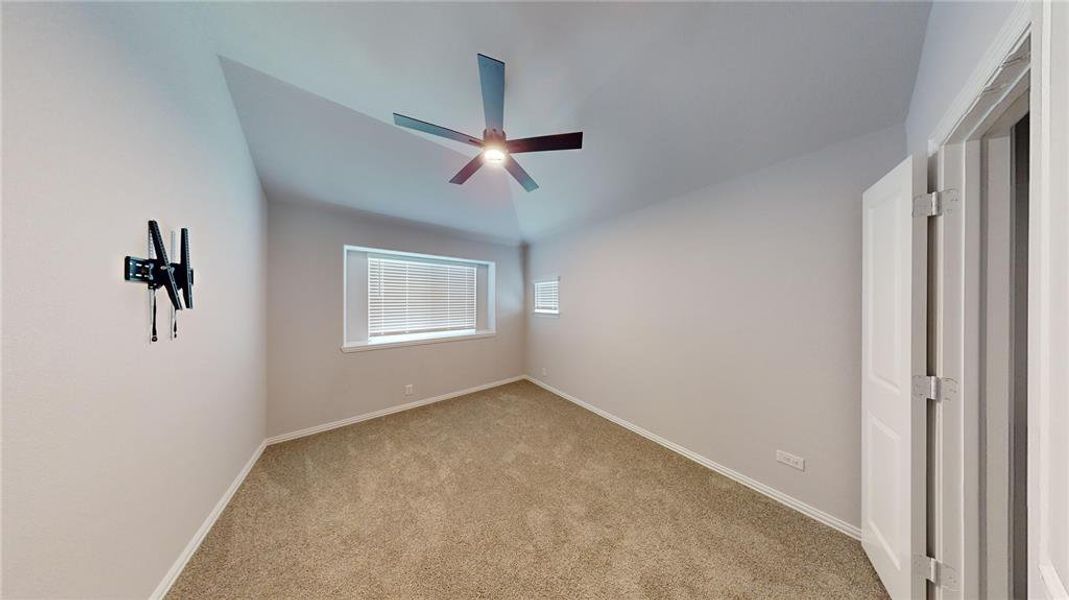 Carpeted empty room featuring lofted ceiling and ceiling fan