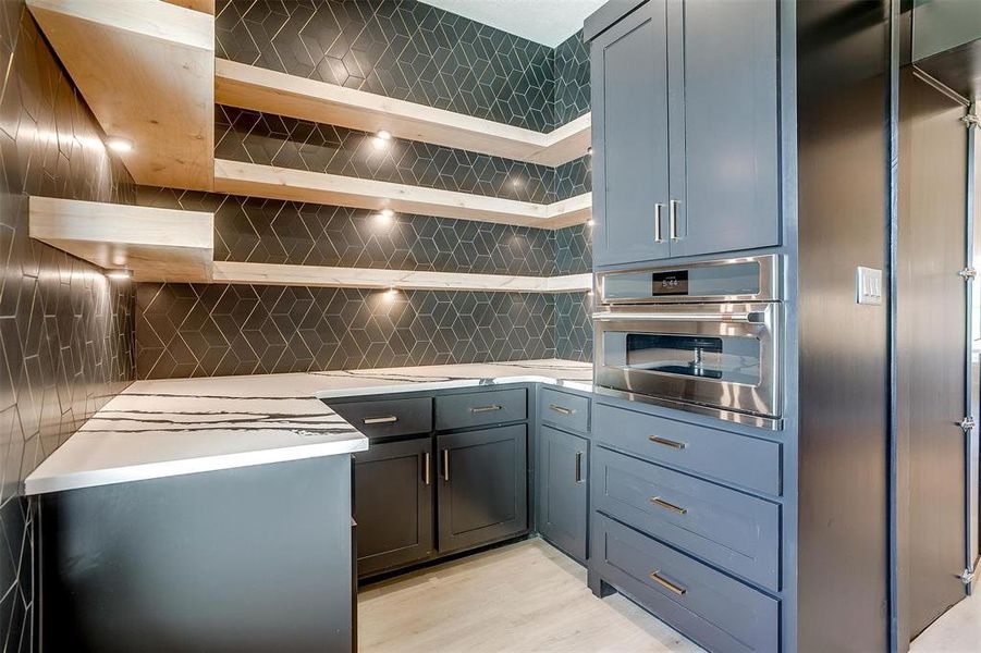 Kitchen featuring stainless steel oven, light hardwood / wood-style floors, and tasteful backsplash
