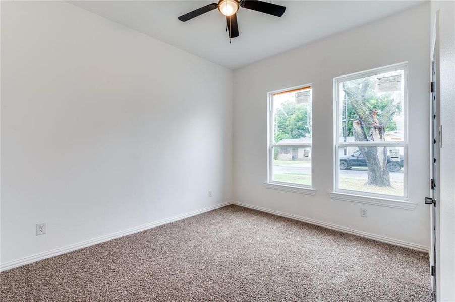 Carpeted spare room featuring ceiling fan and a wealth of natural light