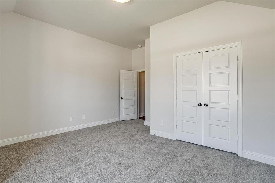 Unfurnished bedroom with light carpet, vaulted ceiling, and a closet