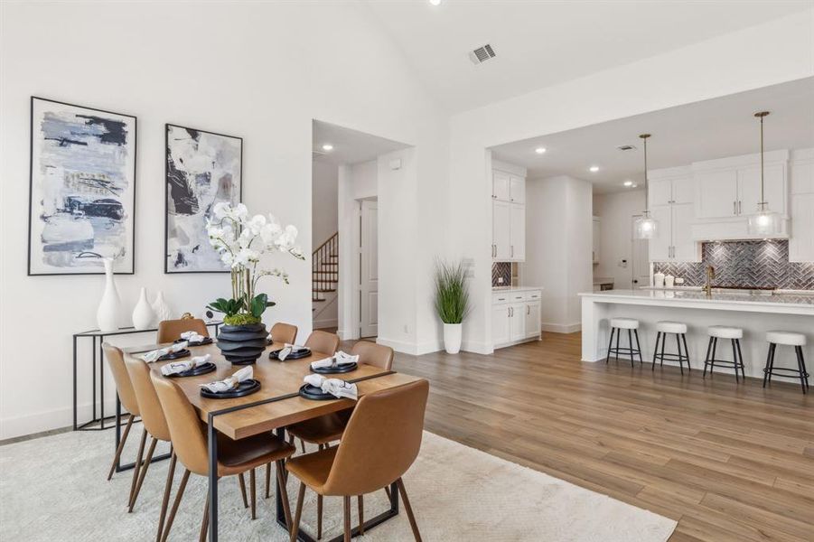 Dining area with light hardwood / wood-style flooring and high vaulted ceiling