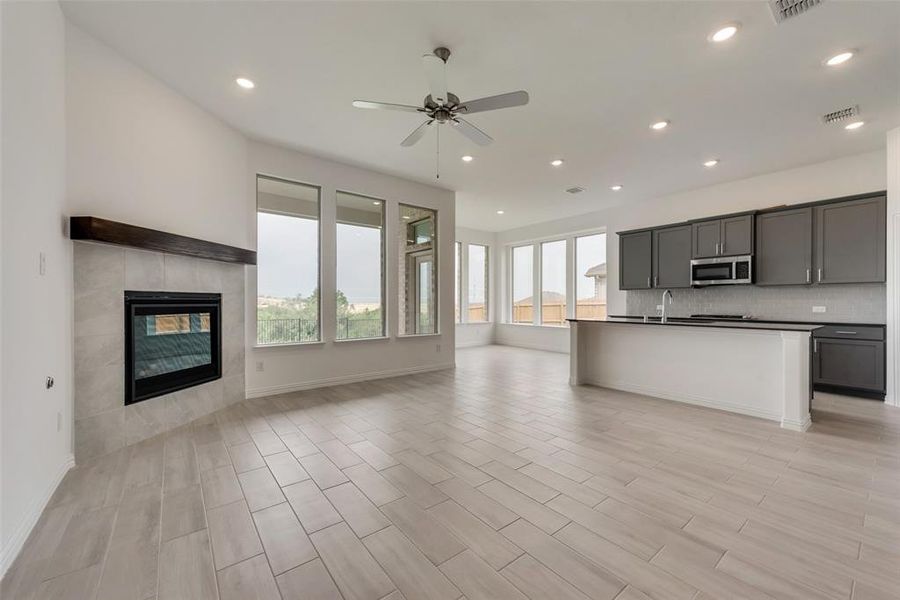 Kitchen featuring an island with sink, light wood-type flooring, a fireplace, and ceiling fan