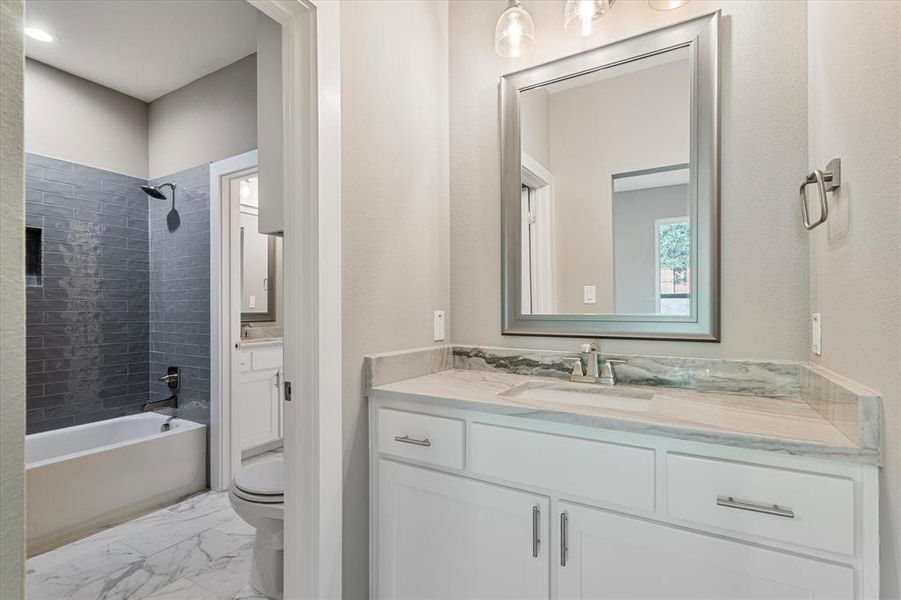 Full bathroom featuring tiled shower / bath combo, toilet, tile patterned floors, and vanity