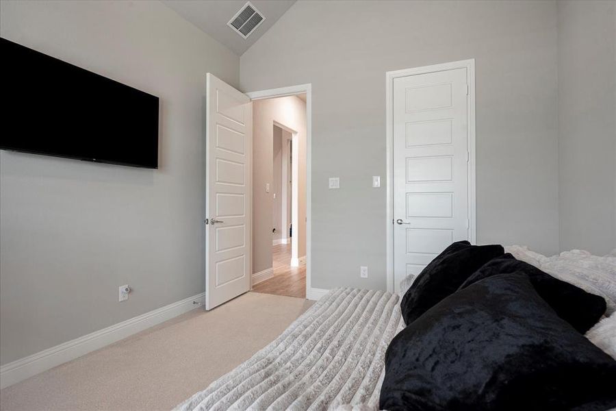 Bedroom with light carpet and vaulted ceiling