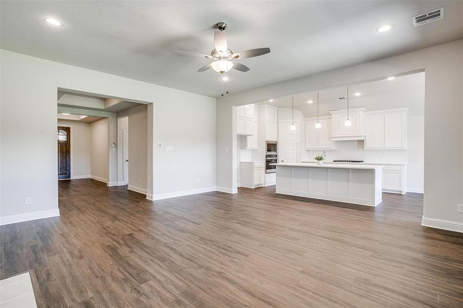 Unfurnished living room featuring ceiling fan and hardwood / wood-style floors