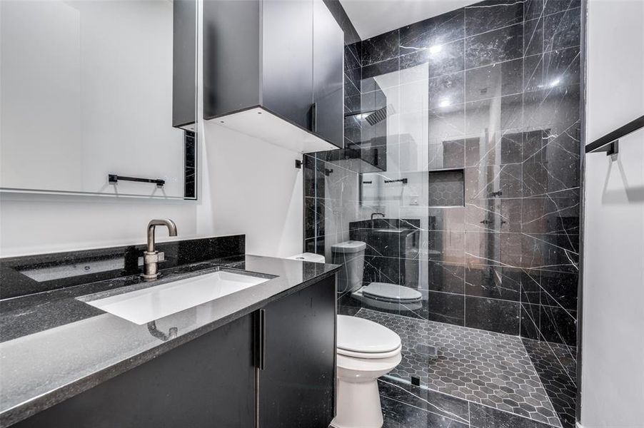 Bathroom featuring vanity, toilet, and a tile shower