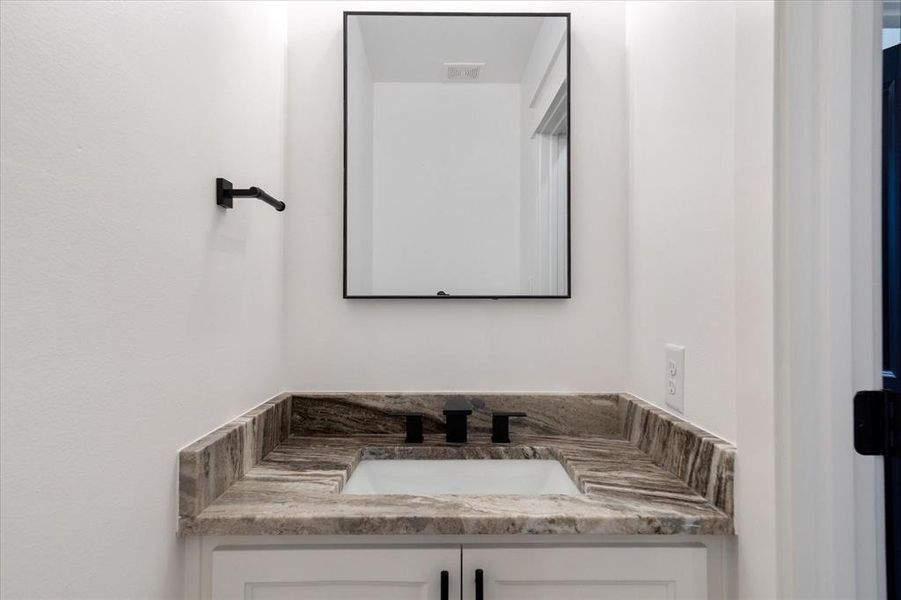 The powder bath located on the first level. Granite countertops, an undermount sink & sleek hardware adorn this contemporary space.