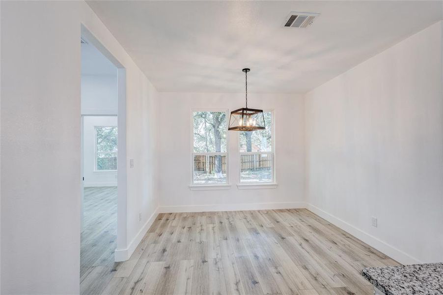 Unfurnished dining area with a chandelier and light hardwood / wood-style floors