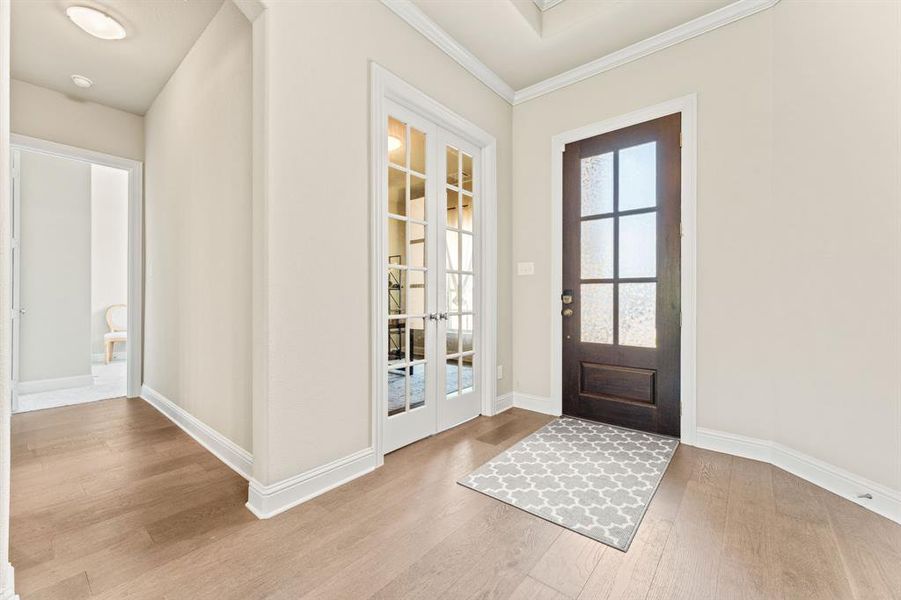 Entryway featuring ornamental molding, french doors, and light wood-type flooring