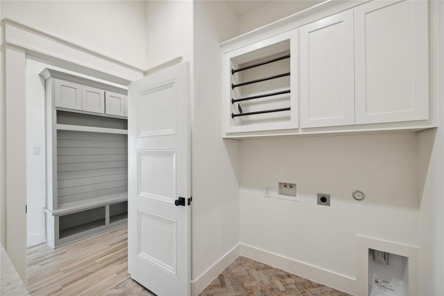 Washroom with washer hookup, cabinets, light hardwood / wood-style floors, electric dryer hookup, and hookup for a gas dryer