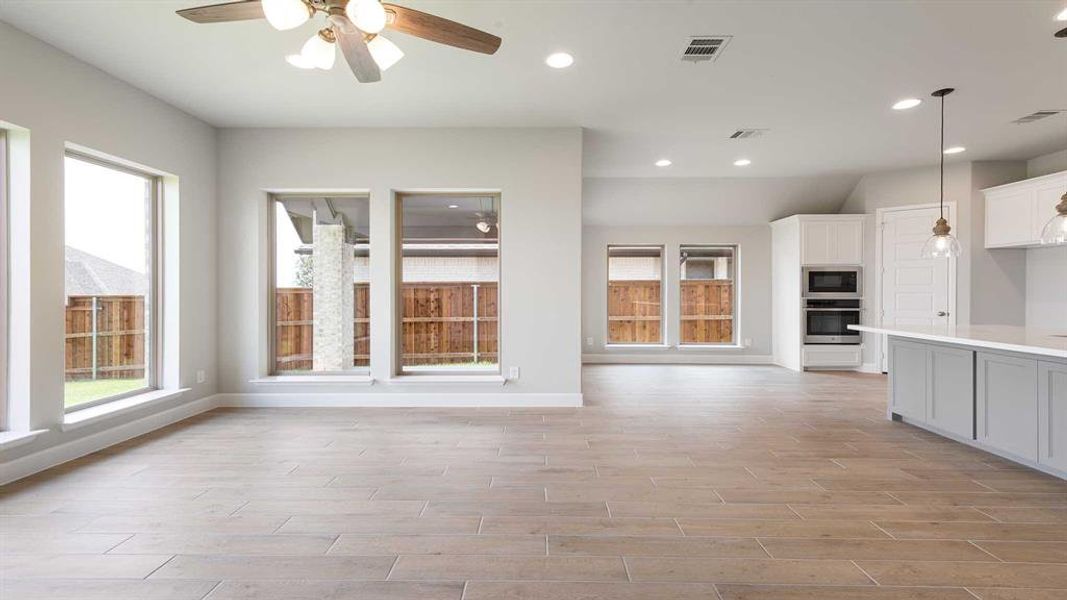 Kitchen featuring white cabinetry, light wood-type flooring, ceiling fan, appliances with stainless steel finishes, and pendant lighting