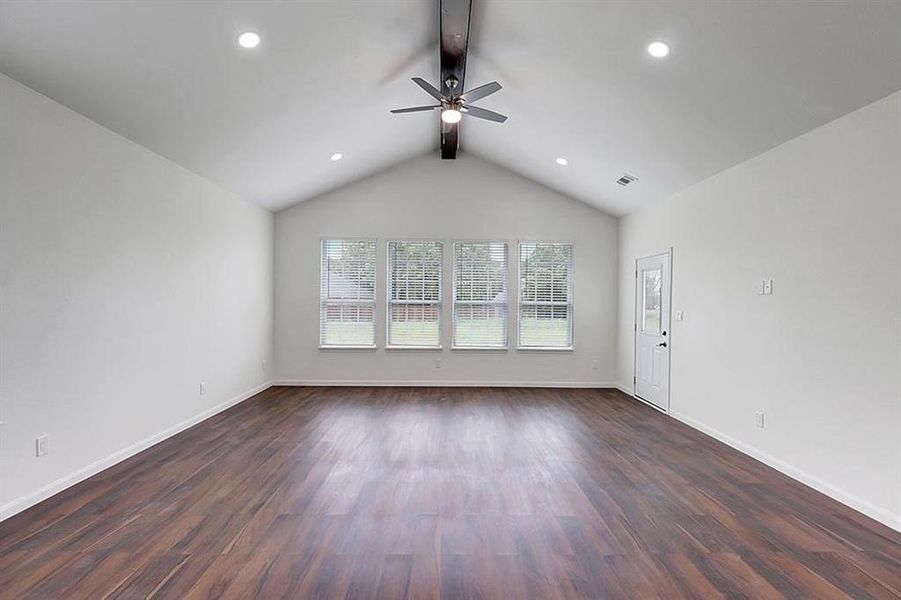 Unfurnished living room with dark wood-type flooring, lofted ceiling with beams, and ceiling fan