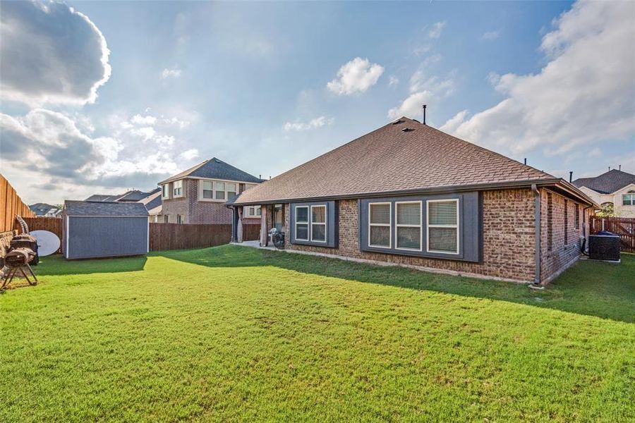 Back of property featuring a lawn, central AC unit, and a shed