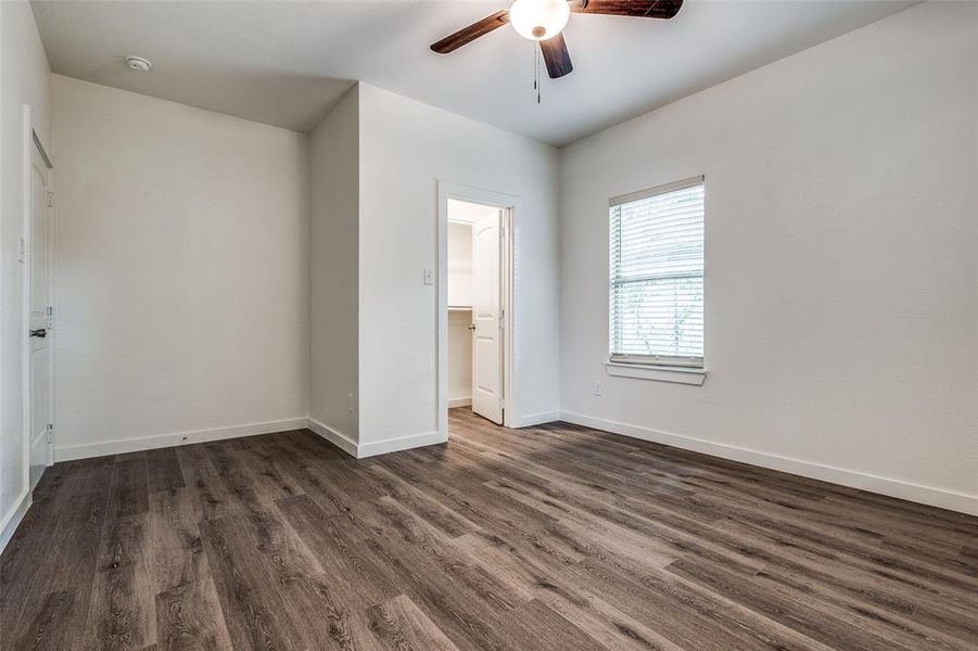 Unfurnished bedroom featuring a spacious closet, ceiling fan, and wood-type flooring