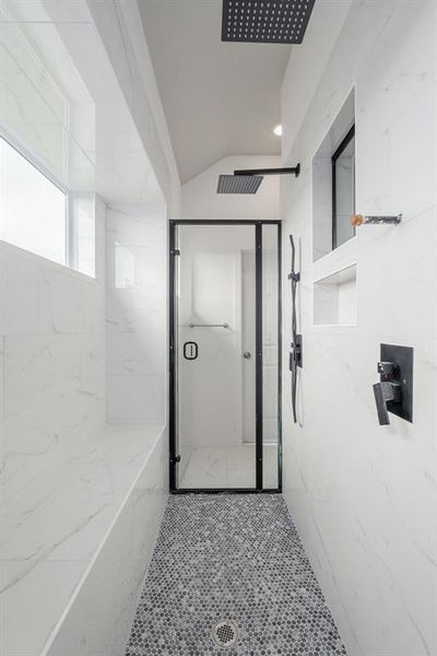 Bathroom with vaulted ceiling, walk in shower, and tile patterned flooring