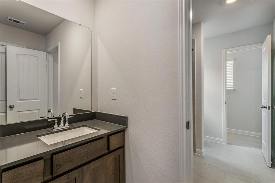 The third bathroom is well-appointed with a stylish vanity, modern fixtures, and a bathtub with a shower. It offers convenience and comfort for family and guests. Photos are from another Rylan floor plan.