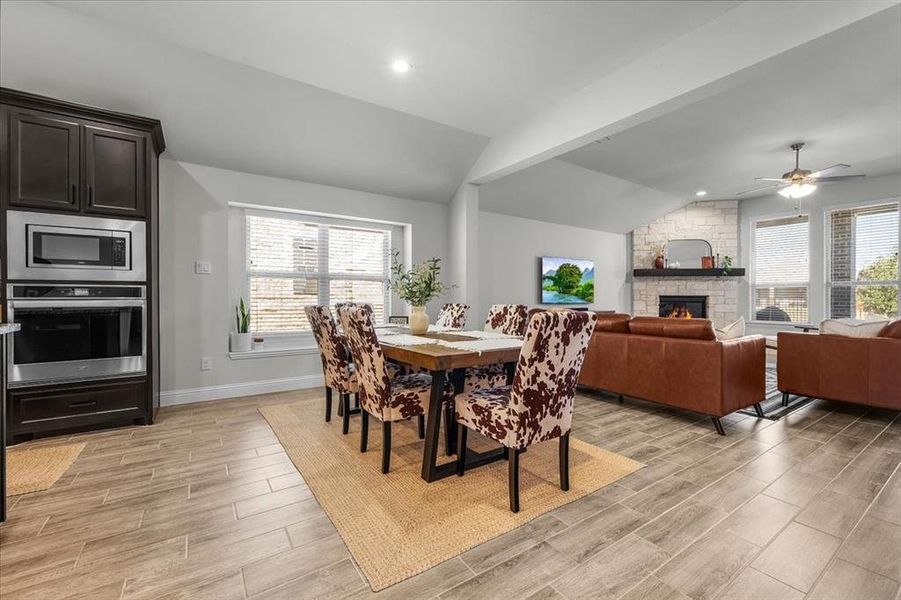 Dining room featuring light hardwood / wood-style flooring, vaulted ceiling, a wealth of natural light, and ceiling fan