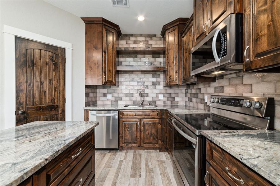 A stunning tile backsplash stretches throughout the kitchen, complementing the sleek design and adding a touch of sophistication. Abundant counter space offers ample room for organizing and storing all your kitchen essentials. Completing this well-equipped culinary space is a convenient walk-in pantry, providing additional storage to keep your kitchen organized and efficient.