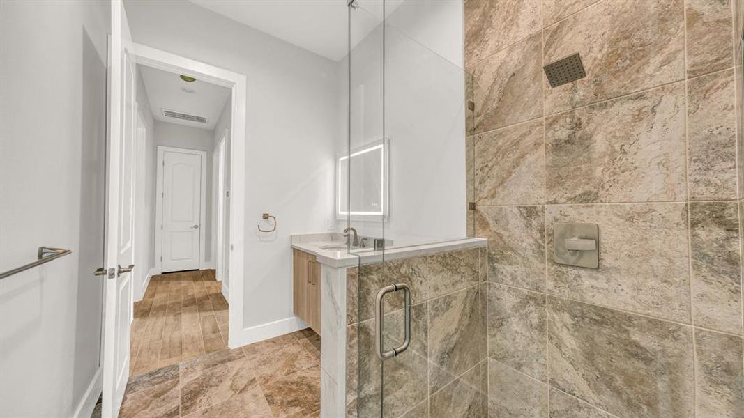 Bathroom featuring a tile shower, hardwood / wood-style flooring, vanity, and toilet