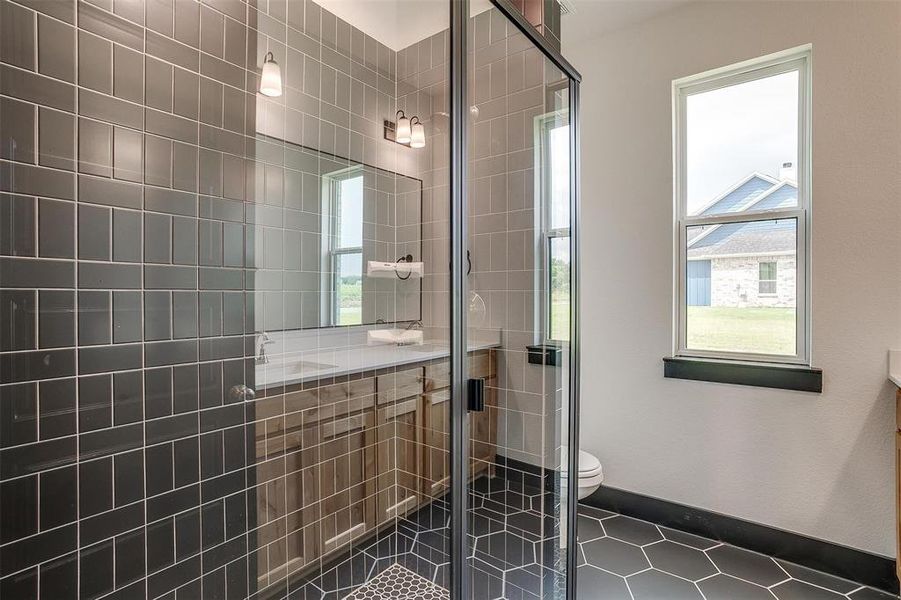 Bathroom featuring tile flooring, walk in shower, vanity, and toilet