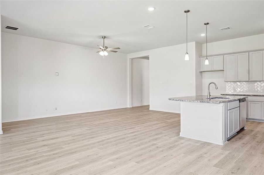 Kitchen with a kitchen island with sink, ceiling fan, backsplash, sink, and light hardwood / wood-style floors