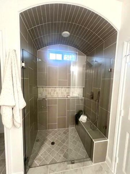 Bathroom featuring a shower with door, vaulted ceiling, and tile patterned floors