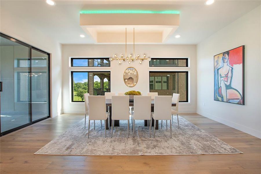 Unfurnished dining area with a notable chandelier, hardwood / wood-style floors, and a raised ceiling