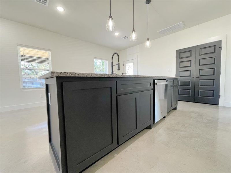 Kitchen featuring a kitchen island with sink, decorative light fixtures, sink, and dishwasher