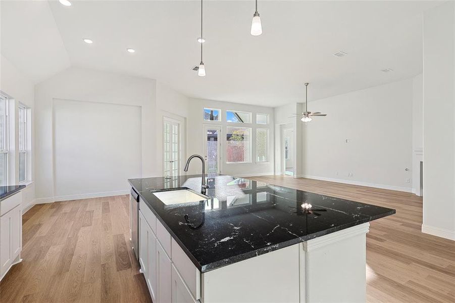 Kitchen featuring pendant lighting, white cabinetry, sink, a center island with sink, and light hardwood / wood-style floors