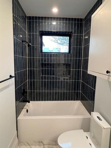 This photo showcases a modern and spacious full bathroom in the unit, complete with a walk-in shower, bathtub, sink, toilet, and ample storage space.