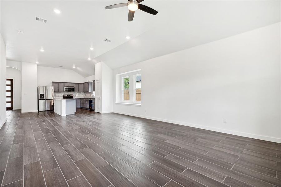 Unfurnished living room featuring lofted ceiling, ceiling fan, and dark hardwood / wood-style flooring