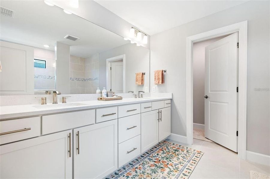 The primary bathroom has a double-sink vanity with lots of drawers for storage and toilet room.