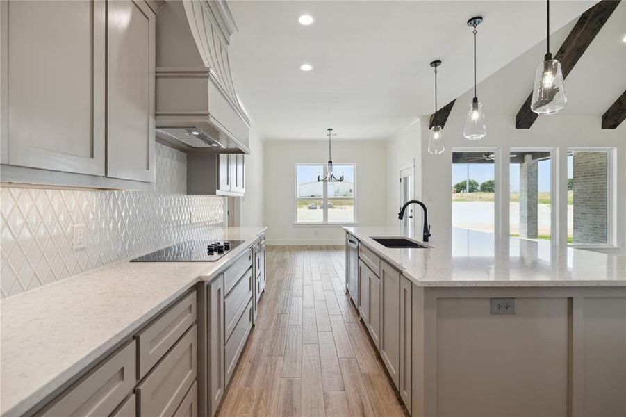 Kitchen with black electric cooktop, light hardwood / wood-style flooring, sink, and light stone countertops