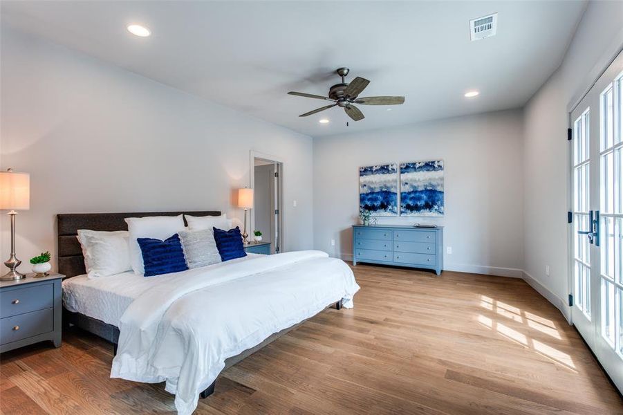 Bedroom with ceiling fan, multiple windows, and light hardwood / wood-style flooring