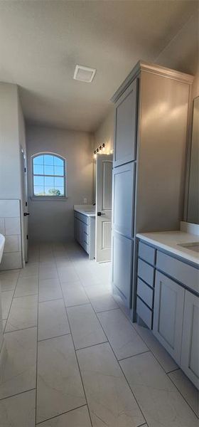 Primary bathroom with dual sinks and additional cabinetry