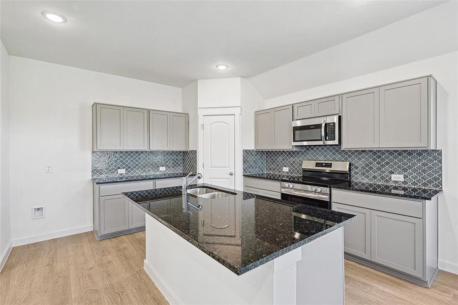 Kitchen featuring backsplash, light wood-type flooring, appliances with stainless steel finishes, sink, and gray cabinets